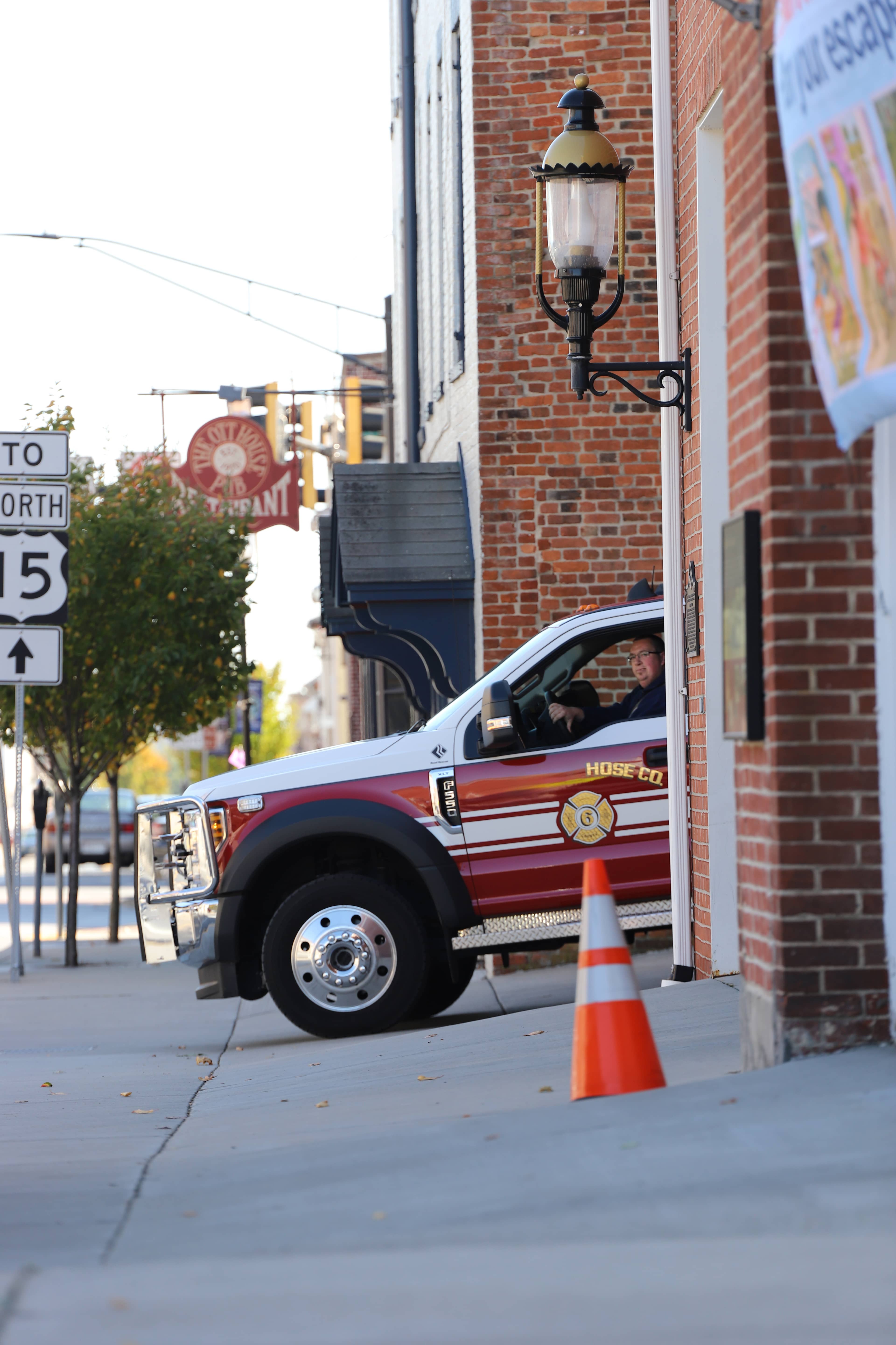 Fire truck pulling onto the street past a brick building during a response