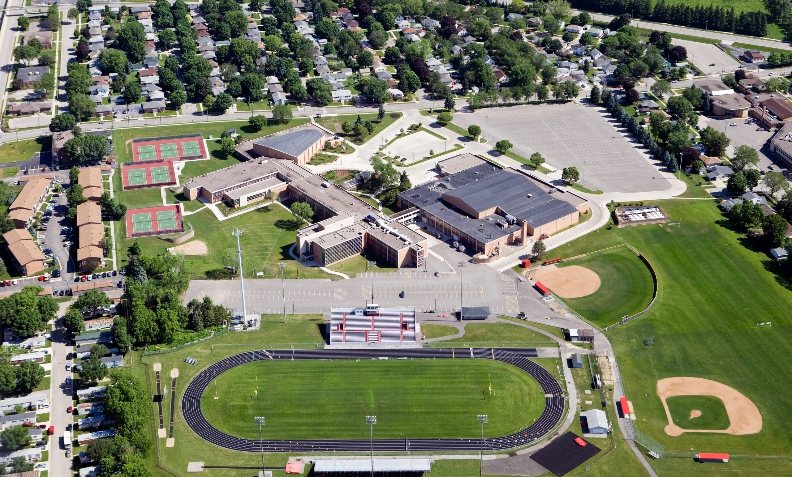Aerial view of a school campus with athletic fields, tennis courts, and a track