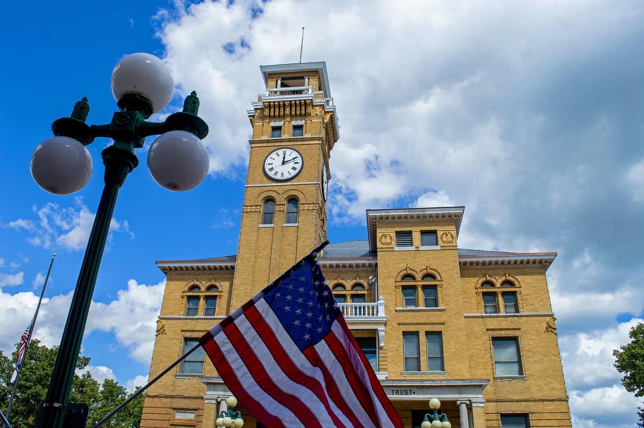 Historic municipal courthouse with a clock tower and U.S. flag